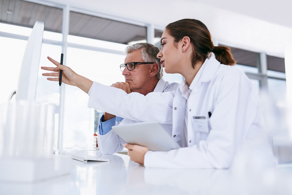 Image of two physicians in a medical lab looking at a computer monitor